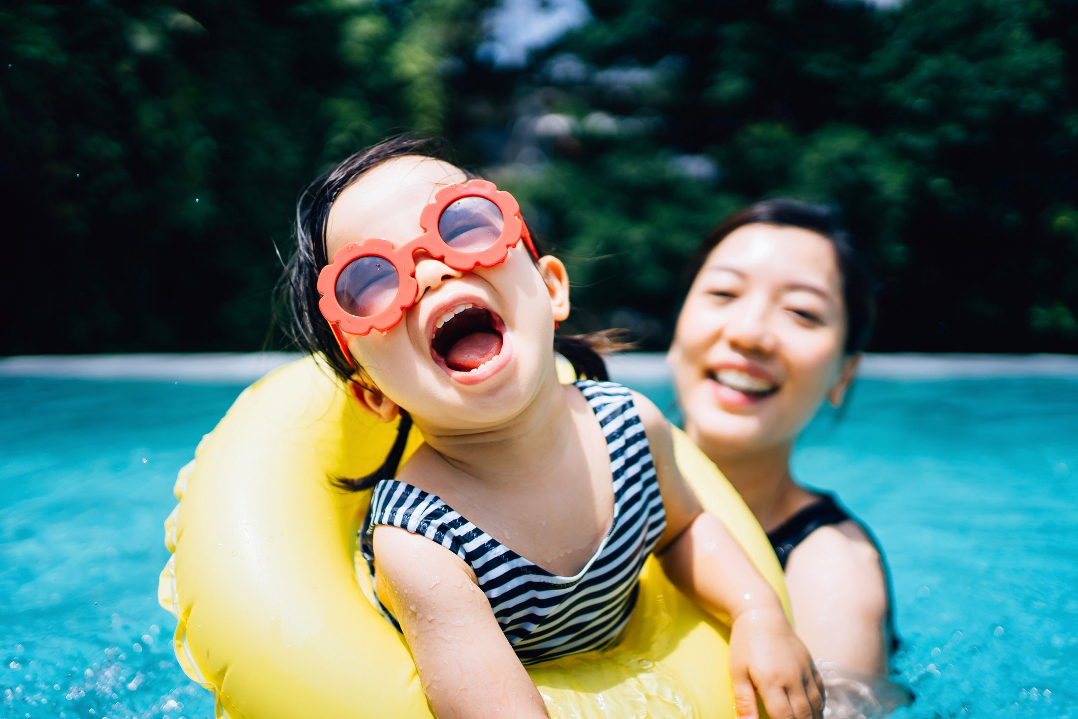 Young girl and mom swimming in a pool